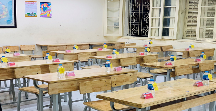 A classroom with many desks and water bottlesDescription automatically generated